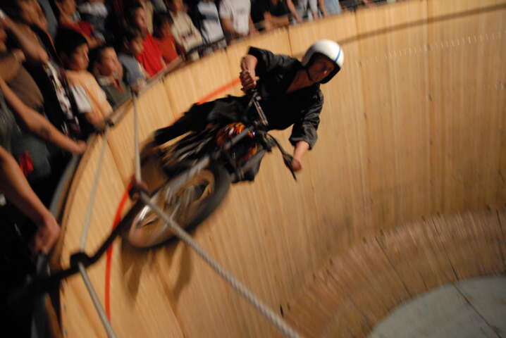 Quartier rouge - Le Mur de la Mort - Le public est perché en hauteur et contemple les pilotes qui jouent avec les limites du cylindre. 