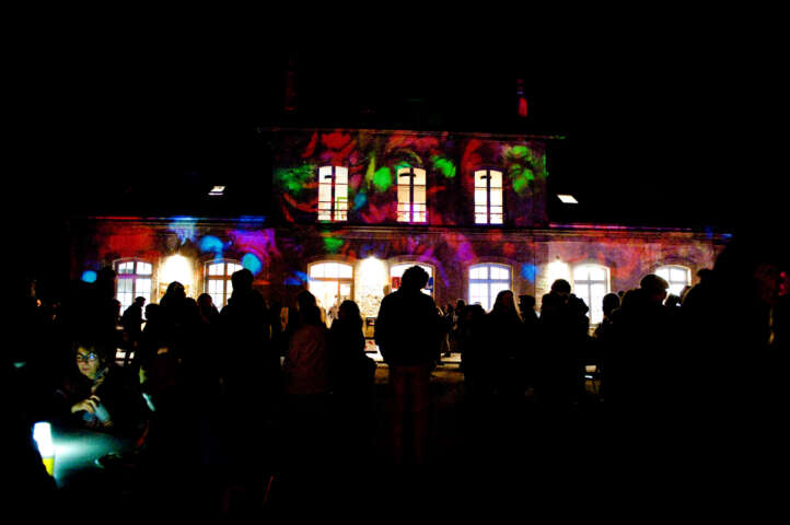 Quartier rouge - La gare en commun - La façade de la gare illuminée par la compagnie Delirium Lumens.